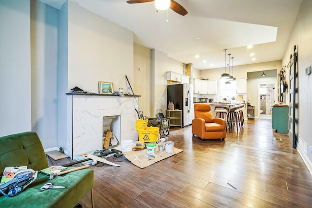 living room featuring baseboards, ceiling fan, a premium fireplace, and wood finished floors