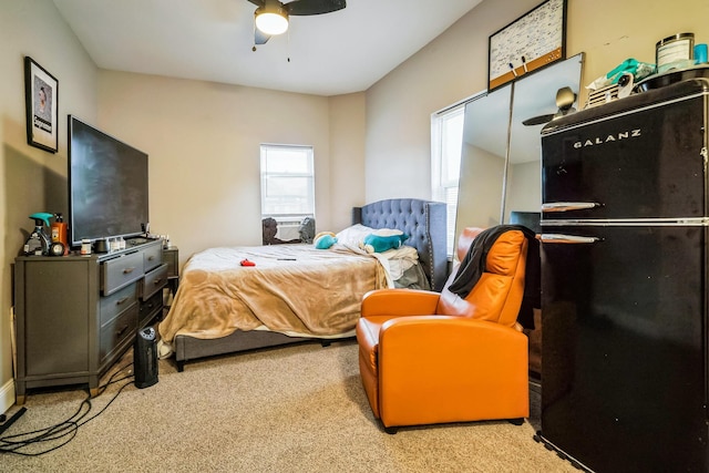 bedroom featuring light carpet, freestanding refrigerator, and a ceiling fan