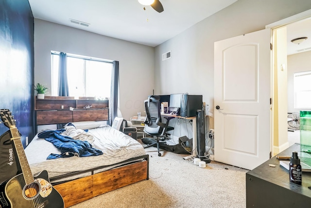 carpeted bedroom featuring multiple windows, visible vents, and a ceiling fan