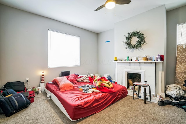 carpeted bedroom with a fireplace and ceiling fan