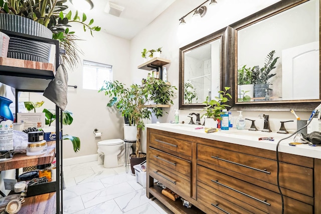 full bathroom with marble finish floor, double vanity, toilet, a sink, and baseboards