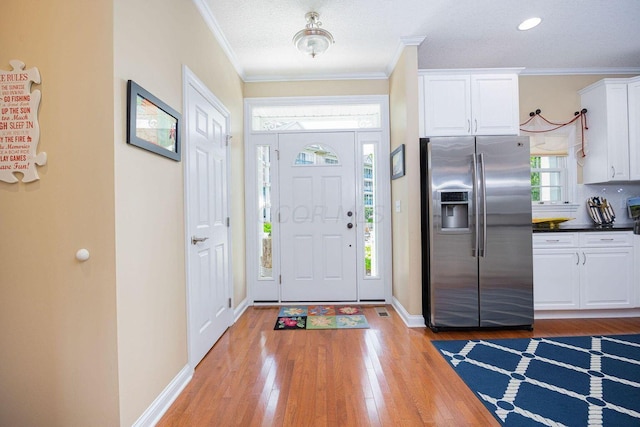 foyer featuring light wood finished floors, baseboards, and ornamental molding