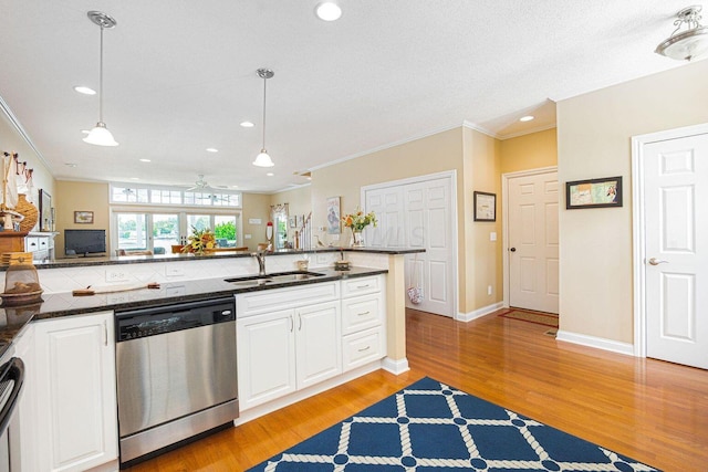 kitchen featuring a sink, white cabinets, ornamental molding, stainless steel dishwasher, and light wood finished floors