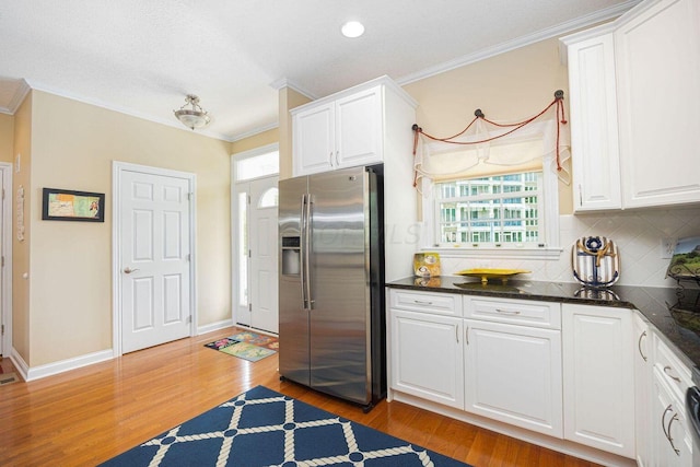 kitchen featuring stainless steel refrigerator with ice dispenser, white cabinetry, and crown molding