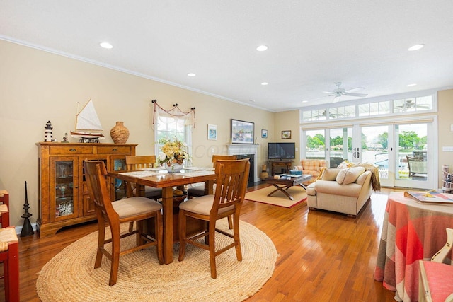 dining space featuring light wood finished floors, recessed lighting, crown molding, and a tile fireplace