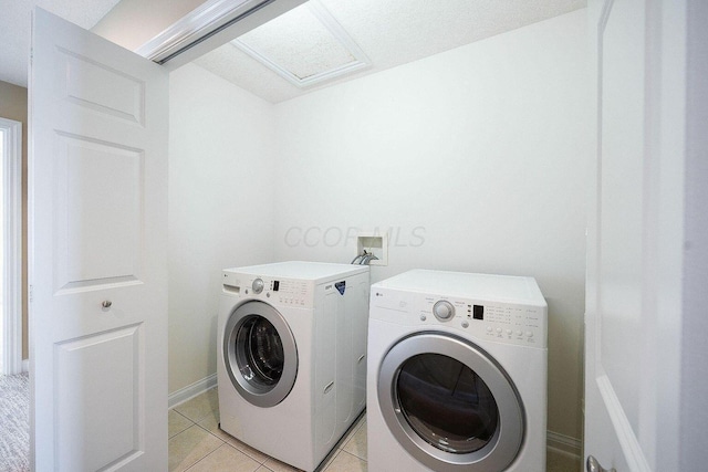 laundry area with light tile patterned floors, laundry area, washing machine and clothes dryer, and attic access