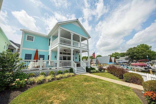 view of front facade featuring a porch, a ceiling fan, a front yard, fence, and a balcony