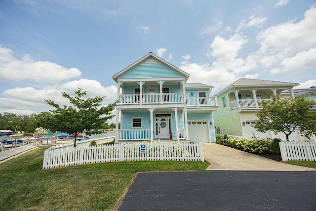 view of front of property featuring a balcony, a fenced front yard, a porch, and concrete driveway