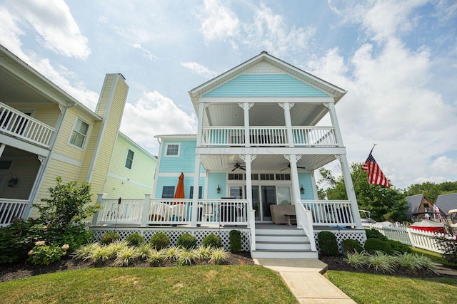 view of front of house with a balcony, covered porch, a front lawn, and a ceiling fan