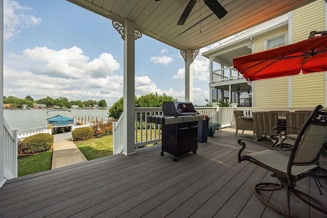 wooden deck with a water view, a grill, and a ceiling fan