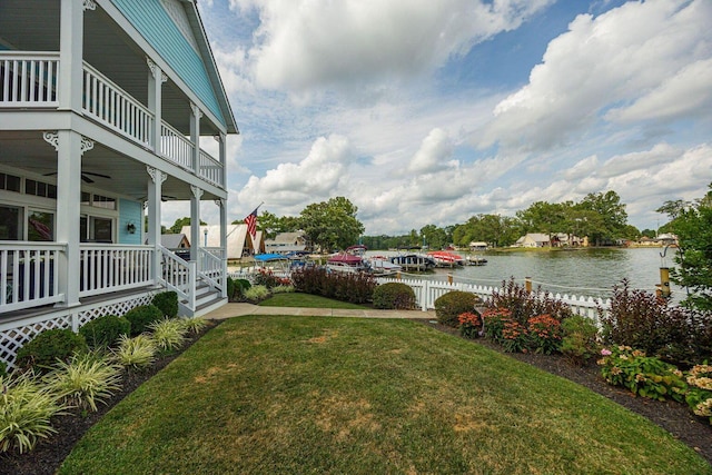 view of yard featuring a water view, a balcony, fence, and covered porch