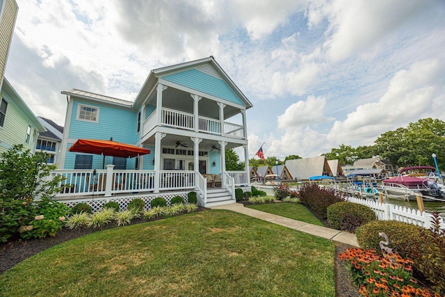 view of front of house with a balcony, ceiling fan, fence, a porch, and a front yard