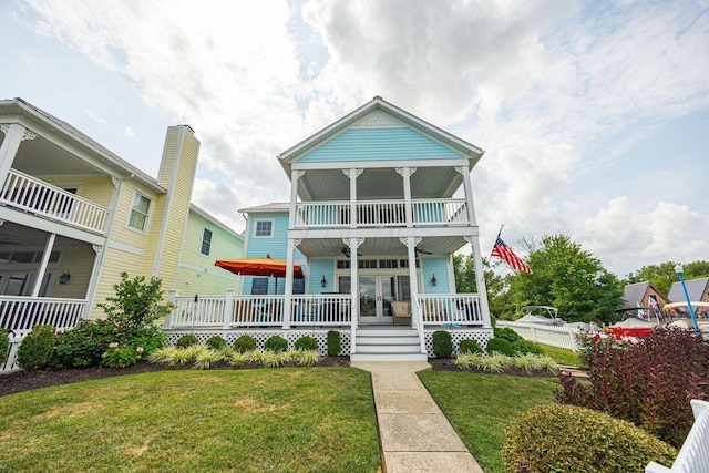 view of front facade featuring covered porch, french doors, a front lawn, and a balcony