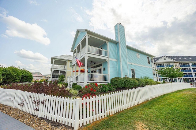 exterior space with a balcony, a fenced front yard, a chimney, and a yard