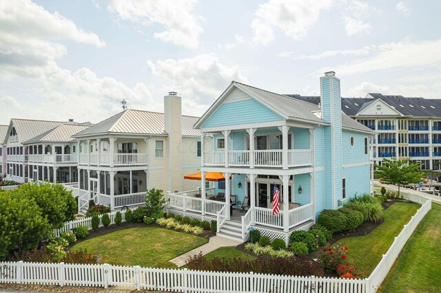 back of house featuring a balcony, a fenced front yard, and a porch