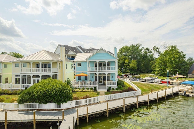 rear view of property featuring metal roof, a standing seam roof, a water view, and fence