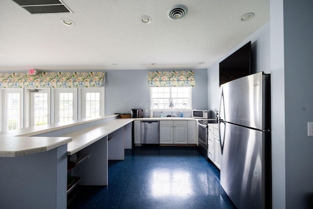 kitchen featuring dark floors, recessed lighting, stainless steel appliances, visible vents, and light countertops