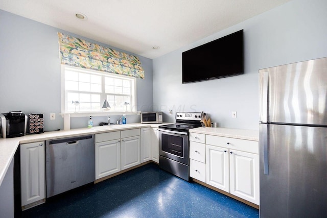 kitchen featuring white cabinets, stainless steel appliances, a sink, and light countertops