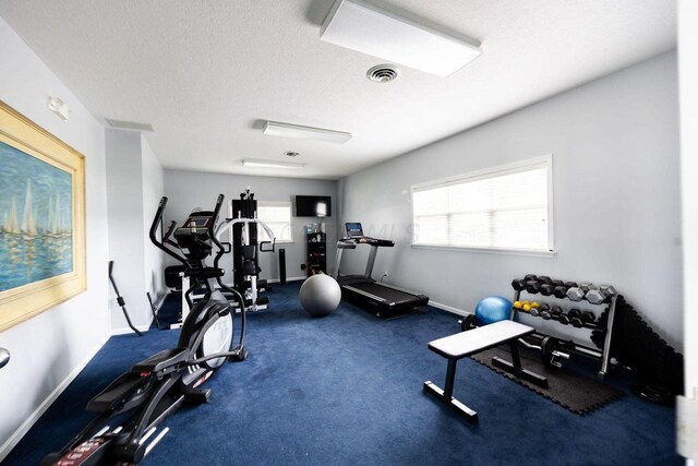 workout room featuring plenty of natural light, visible vents, baseboards, and a textured ceiling