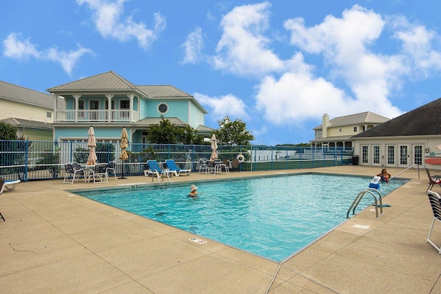 pool featuring french doors, a patio area, and fence