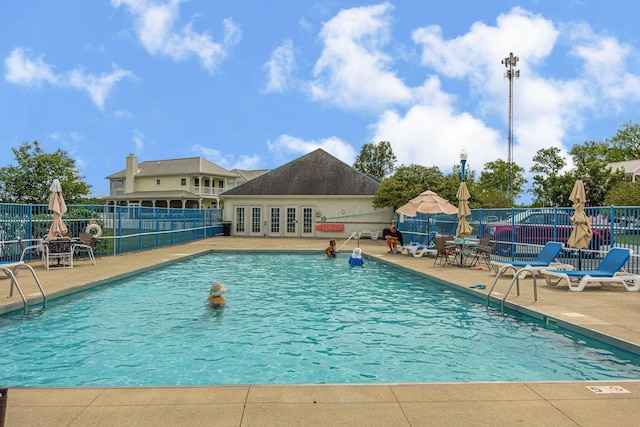 community pool featuring french doors, fence, and a patio