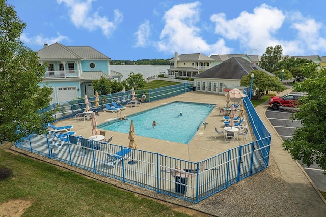 pool featuring a water view, fence, and a patio