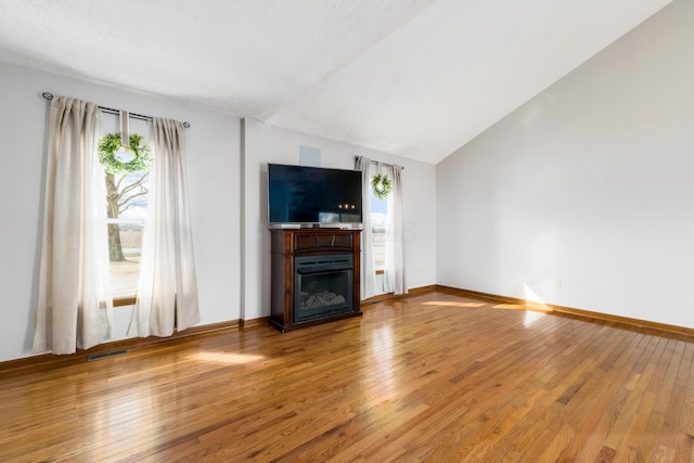 unfurnished living room featuring wood-type flooring, a fireplace, baseboards, and vaulted ceiling