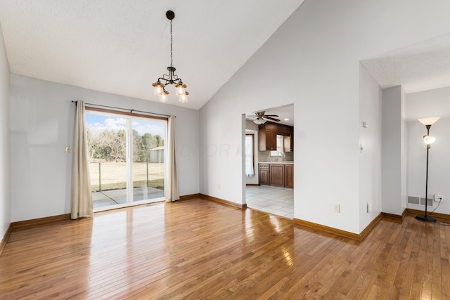 interior space with light wood finished floors, baseboards, visible vents, an inviting chandelier, and a sink