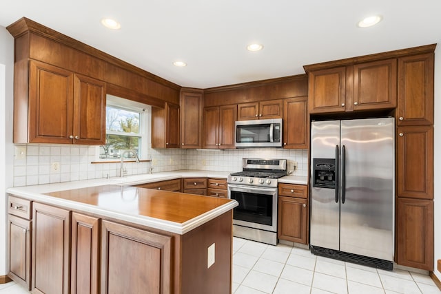 kitchen featuring appliances with stainless steel finishes, brown cabinetry, light countertops, and tasteful backsplash