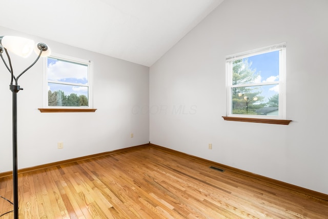 unfurnished room with lofted ceiling, baseboards, visible vents, and light wood finished floors