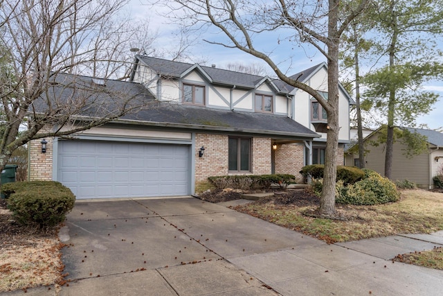 tudor-style house with concrete driveway, brick siding, roof with shingles, and an attached garage