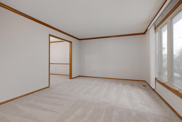 spare room with light carpet, ornamental molding, visible vents, and baseboards