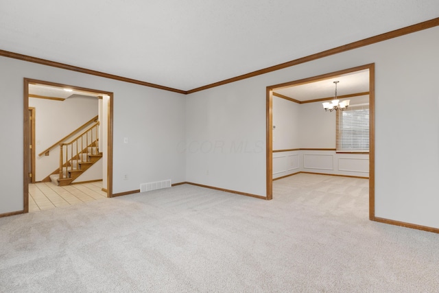 spare room featuring carpet, crown molding, a notable chandelier, visible vents, and stairs