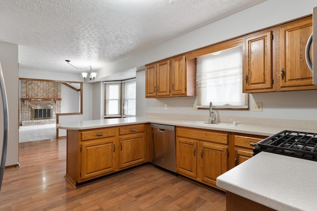 kitchen featuring dishwasher, wood finished floors, a peninsula, light countertops, and a sink