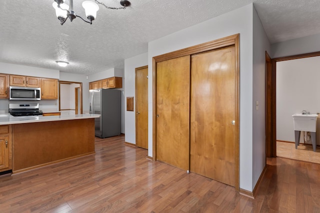 kitchen featuring appliances with stainless steel finishes, brown cabinetry, and wood finished floors