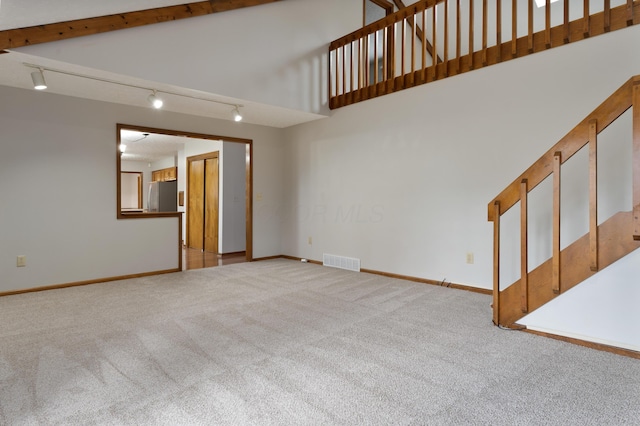 unfurnished living room with carpet, a high ceiling, visible vents, and baseboards