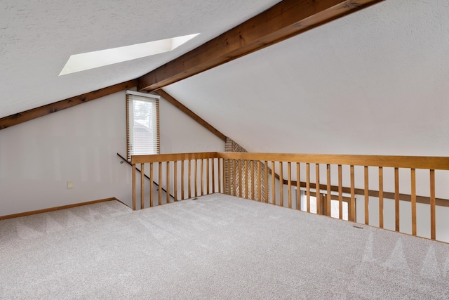 bonus room featuring lofted ceiling with skylight, carpet flooring, and a textured ceiling