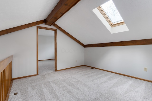 additional living space featuring carpet floors, vaulted ceiling with skylight, visible vents, and baseboards