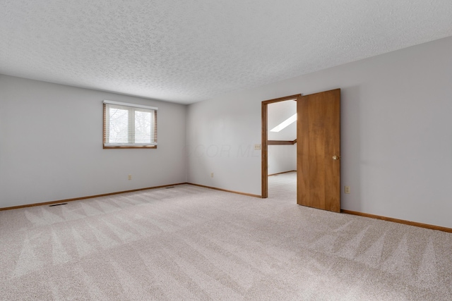 carpeted empty room with a textured ceiling, visible vents, and baseboards