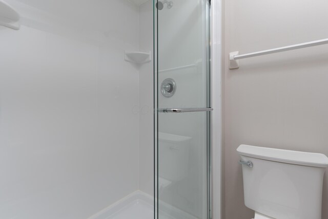 bathroom featuring toilet and a shower stall