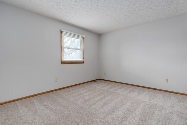 unfurnished room featuring a textured ceiling, baseboards, and light colored carpet