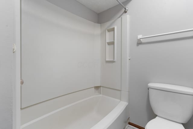 bathroom featuring toilet, shower / washtub combination, and a textured ceiling