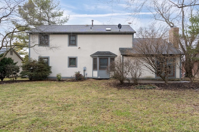 back of house with a lawn, a chimney, and stucco siding