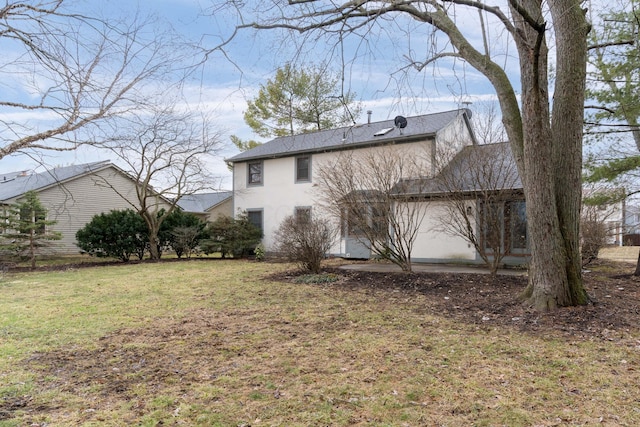 rear view of property featuring a lawn and stucco siding