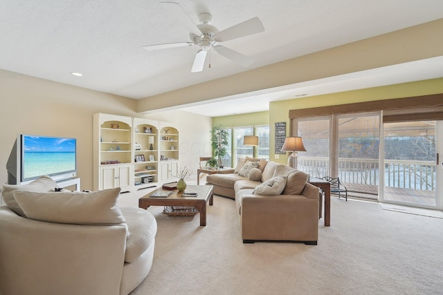 living area featuring a textured ceiling, a ceiling fan, and light colored carpet