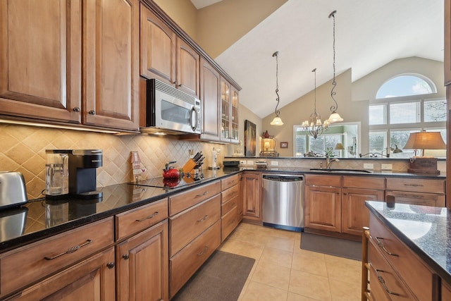 kitchen featuring glass insert cabinets, a sink, appliances with stainless steel finishes, brown cabinets, and decorative light fixtures