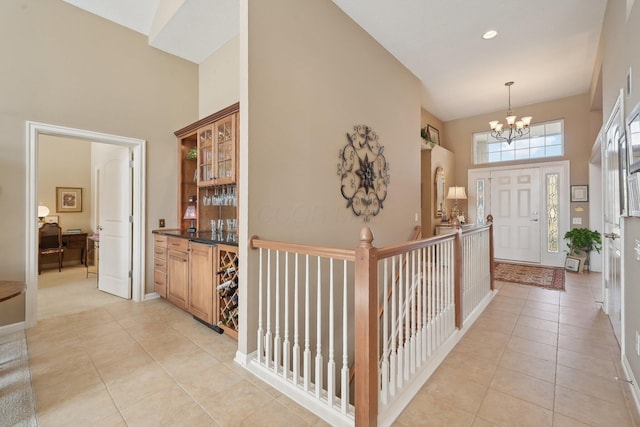 entryway with baseboards, a notable chandelier, a high ceiling, and light tile patterned floors