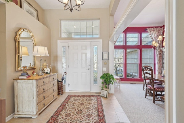 entryway featuring a notable chandelier, a high ceiling, light tile patterned floors, and light colored carpet