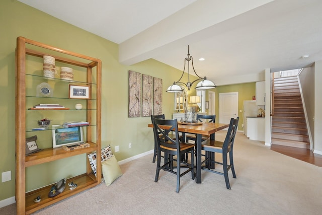 dining area with beam ceiling, light colored carpet, baseboards, and stairs