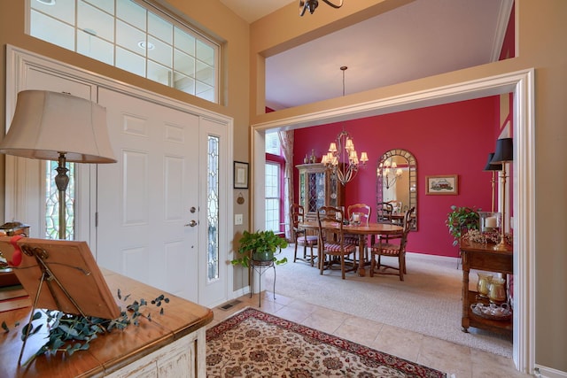 foyer entrance with a chandelier, light tile patterned flooring, light carpet, visible vents, and baseboards